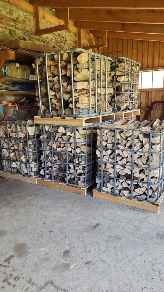 Gestapeltes Brennholz in Metallboxen im Lager